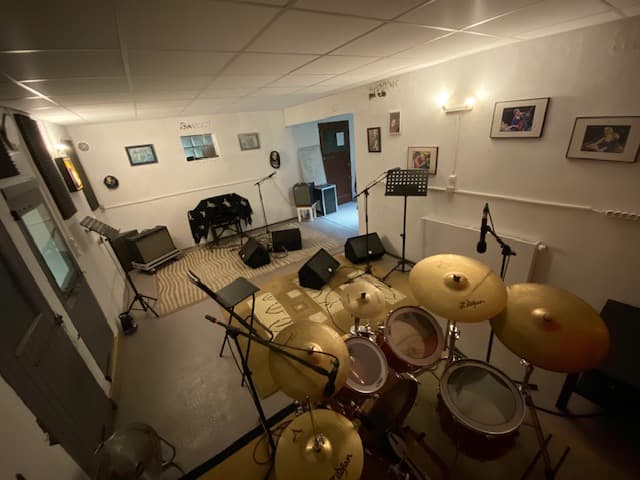 Batterie et cymbales Zildjian au premier plan, retours de scène et pupitres dans le local de répétition de Rotormusik à Carpentras